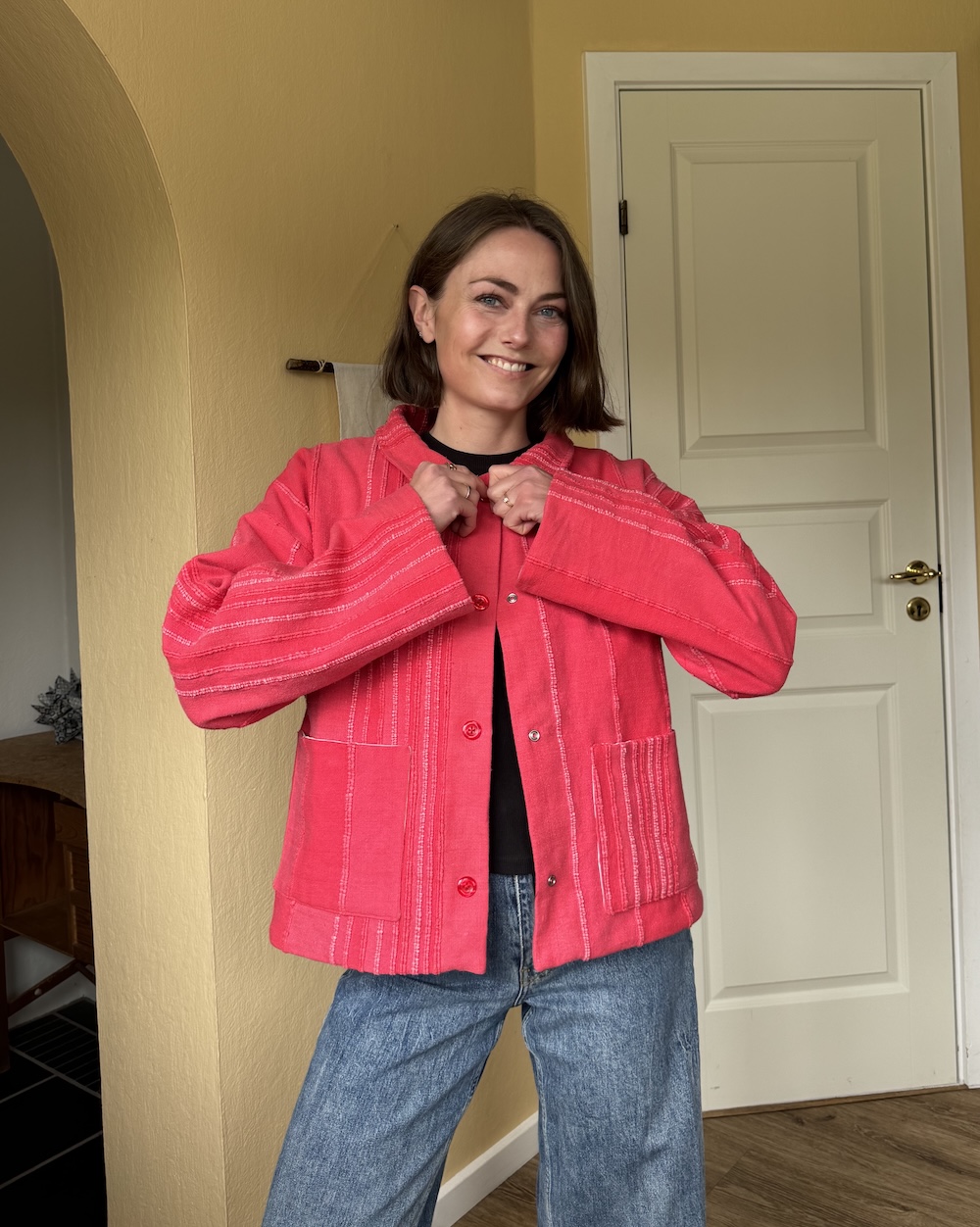 Billede af mig (kvinde) i mit jakkemønster Celia, set tæt på. Den er rød og har knapper med en lille krave.